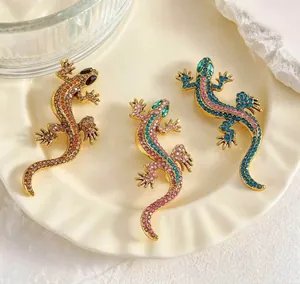 Detail view of three vintage rhinestone-encrusted lizard brooches on a ceramic plate