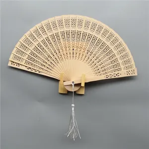 Intricate hollow-carved fragrant wooden folding fan featuring a white silk tassel detail