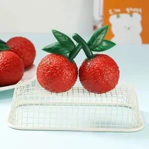 Close-up of realistic red fruit squeeze toy with textured surface and green leaves