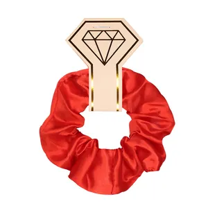 Detailed view of a bright red satin hair scrunchie with diamond-shaped card pack