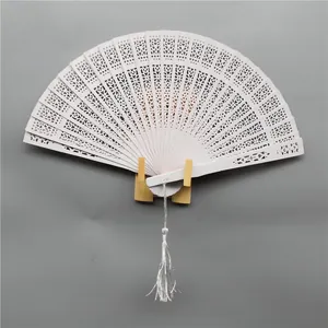 Detail view of an elegant white hollow-out folding wooden fan with a decorative tassel.