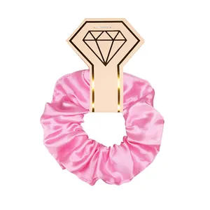 Detail shot of a shiny pink satin scrunchie on a diamond ring shaped display card.