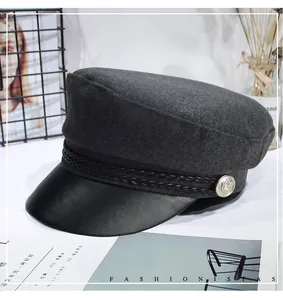 Close-up detail of retro gray newsboy cap with black leather brim and braided trim