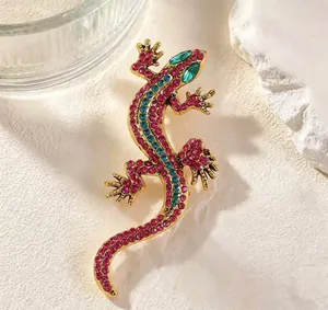 Macro detail of a vintage gold lizard brooch featuring vibrant pink and blue rhinestones