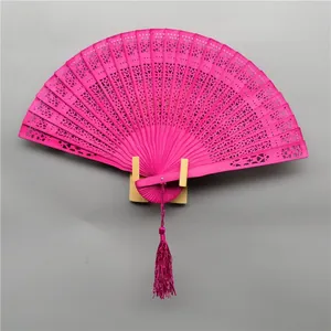 Detail of bright pink folding wooden fan with intricate hollow floral carvings.