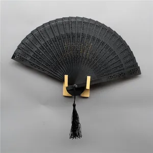 Detailed view of an elegant black hollow carved wooden folding fan with tassel