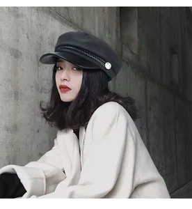 Vintage black baker boy hat with leather brim worn by a female model outdoors