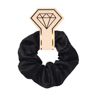 Close-up of black satin scrunchie on a decorative diamond-shaped display card.