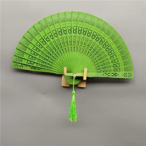 Close-up of elegant green hollow carved wooden folding fan with silk tassel and stand