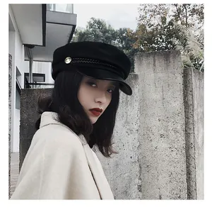 Vintage black newsboy cap with leather brim detail shown on model in an outdoor setting.