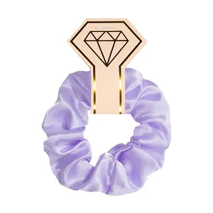 Detailed view of a purple satin scrunchie on a decorative diamond-shaped card.