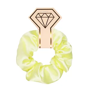 Macro view of a bright yellow satin scrunchie texture on its pink diamond display card.