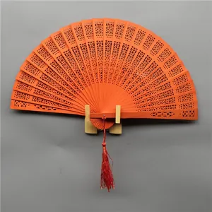 Elegant orange hollow-carved wooden folding fan featuring red tassel and stand