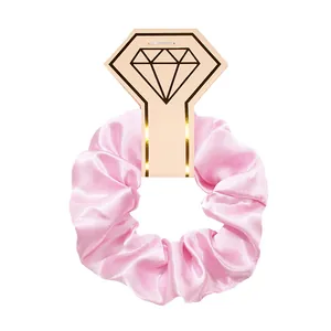 Close-up of a pink satin scrunchie hair tie presented on a diamond graphic display card.