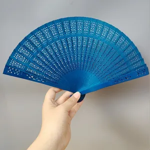 Detailed view of a hand holding an elegant blue hollowed-out wooden folding fan.