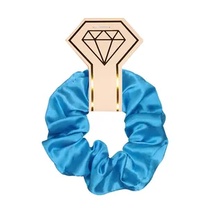 Detailed macro view of a shiny blue satin scrunchie hair tie with diamond card packaging