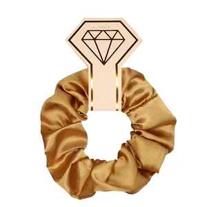 Elegant gold satin silk scrunchie presented on a diamond-shaped card for hair styling