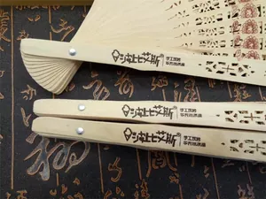 Detail of hollowed wooden folding fan featuring custom laser-engraved logo on the rib