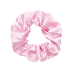 Close-up of pink glossy satin scrunchie with soft ruffled texture