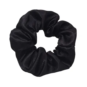 Detailed view of a solid black satin scrunchie hair tie with glossy finish texture