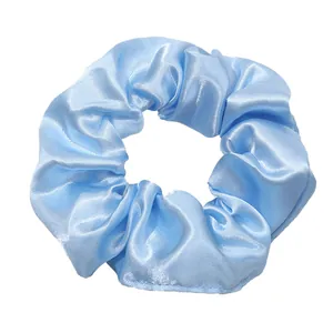 Detail view of a light blue satin hair scrunchie with a glossy silk finish texture
