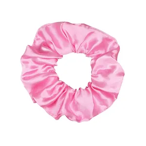 Close-up of a vibrant pink satin scrunchie with a shiny finish and elegant folds.