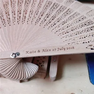 Close-up of personalized engraving on a hollow-out wooden folding fan for weddings