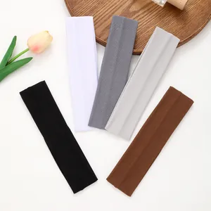 Five multi-color elastic sports headbands arranged on a wooden tray with a tulip.