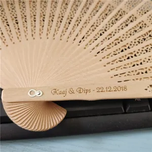 Close-up detail of custom engraved text on an intricate hollow wooden folding fan.