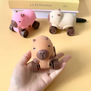 Mano sosteniendo un lindo coche de juguete blandito de capibara sobre fondo amarillo cálido.