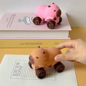Primer plano de un coche de juguete Capybara marrón sostenido sobre libros decorativos.