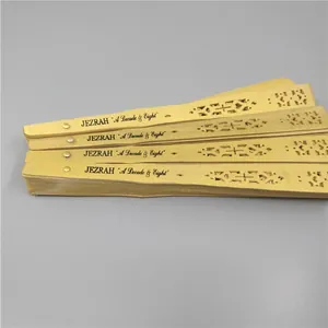 Close-up detail of golden hollow wooden folding fans featuring custom black engraving text