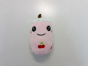 Gros plan d'un porte-clés en peluche rose en forme de thé aux perles avec broderie cerise.