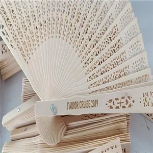 Macro detail of intricate hollowed-out wooden folding fan with J'ADIOR CRUISE engraving.