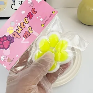 Macro view of a yellow cat paw stress relief squishy toy held in original packaging.