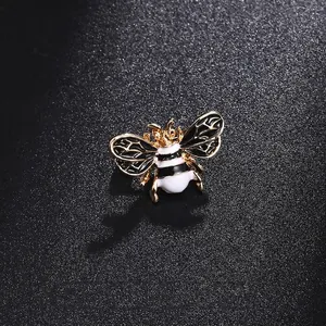 Élégante petite broche abeille avec émail noir et blanc sur fond noir texturé de luxe