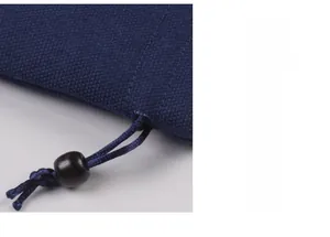 Gros plan d'une pochette à bijoux en tissu bleu avec cordon et perle en bois