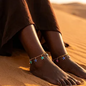 Close-up of bohemian starfish anklets on ankles in a desert sunset setting
