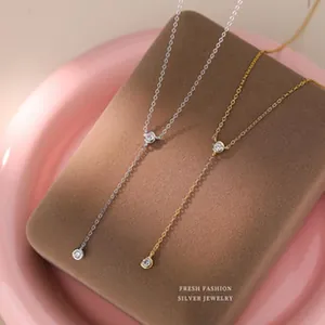 Gros plan détaillé de colliers en Y en argent et dorés ornés de zircons cubiques brillants.