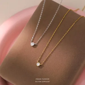 Détail de colliers minimalistes en or et en argent avec des pendentifs ronds en zircone