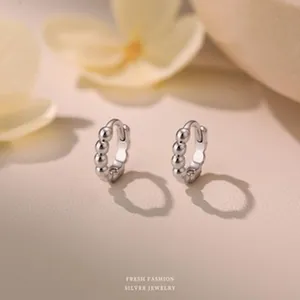 Vue macro détaillée de boucles d'oreilles créoles perlées en argent S999 au fini métallique poli