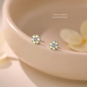 Gros plan détaillé de boucles d'oreilles fleurs en argent avec zircons violets et verts