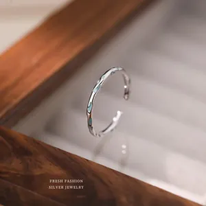 Détail d'une bague ouverte en argent s999 minimaliste avec incrustation d'émail bleu.