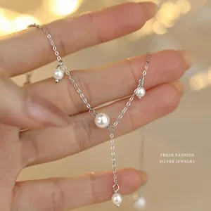 Élégant collier en argent sterling avec de délicates perles blanches tenu à la main vue de près