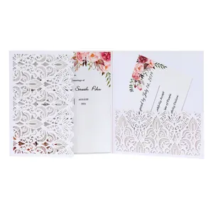 Detailed view of white laser-cut wedding invitation with floral printed insert cards