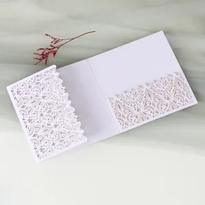 Detail of an elegant white laser-cut wedding invitation card featuring intricate floral patterns