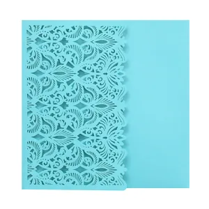 Intricate laser-cut floral pattern on a light blue wedding invitation card detail view