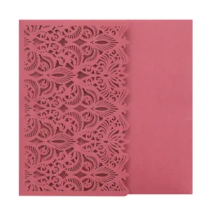 Detail of laser-cut wedding invitation card with intricate floral pattern in dark pink.