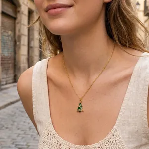 Detail shot of a model wearing a dainty gold necklace with a Christmas tree pendant