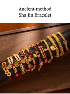 Detail of ancient-style sand gold bracelets with red woven strings and golden charms